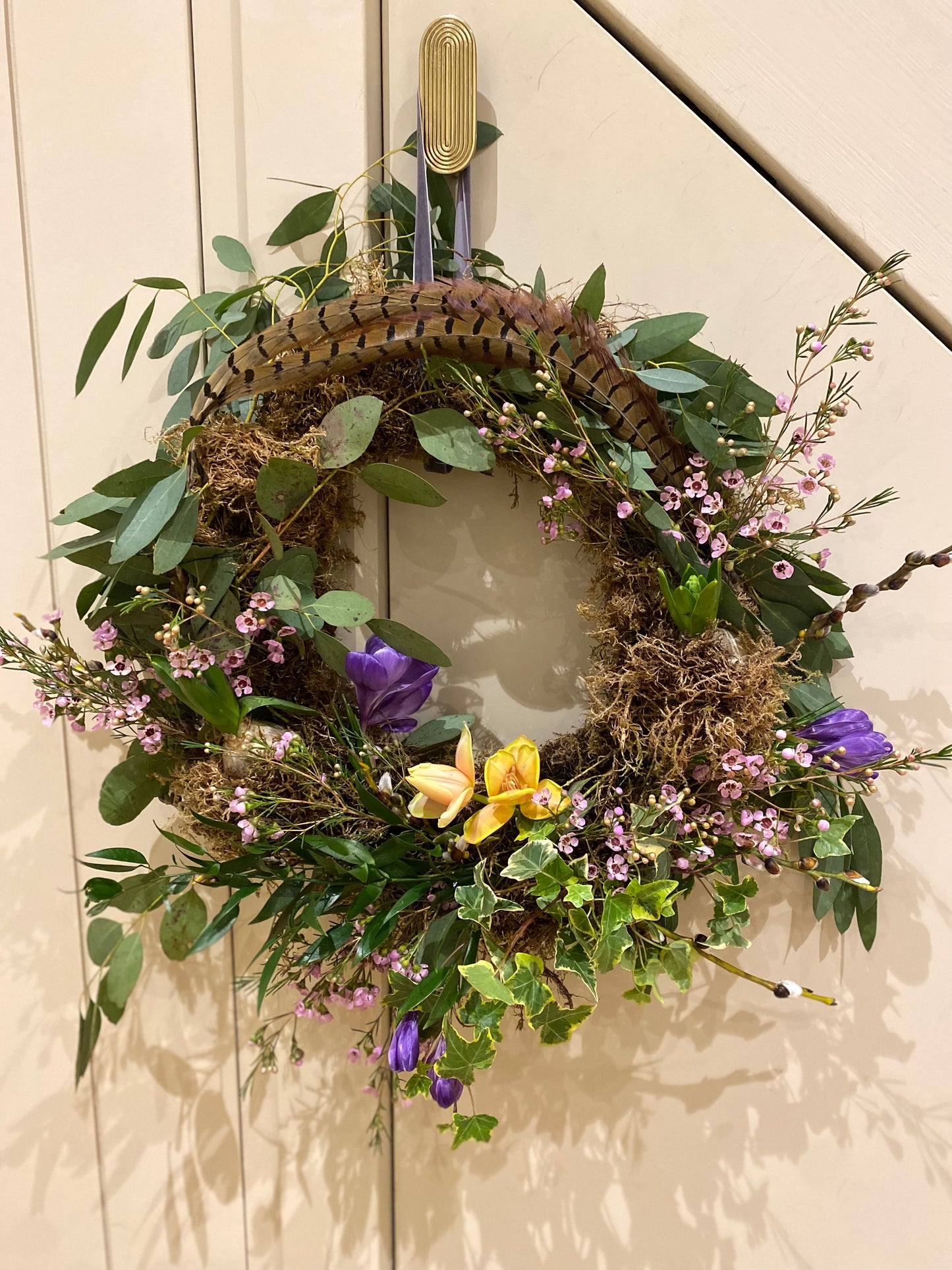 Spring wreath with fresh flowers, foliage and feathers